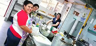 Trois employées Panduit souriantes préparant de la nourriture pour les résidents