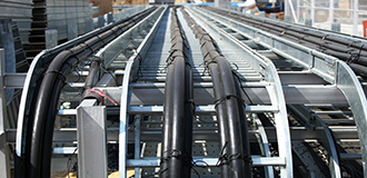 Cables and cable ties adhered to a cable ladder rack outside on a construction site facility