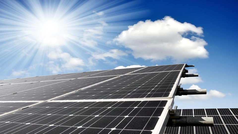 olar panels under a bright blue sky, illuminated by the sun's rays, showcasing renewable energy in action.