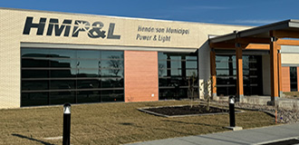 exterior view of a brick and stone building with a sign for Henderson Municipal Power & Light on the front